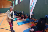 Eine Gruppe von Frauen macht gemeinsam eine Übung mit Ball an der Turnhallenwand. 