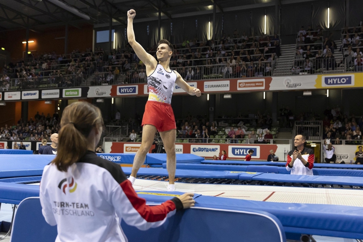 Der Sportler Mathias Schuldt jubelt nach einer erfolgreichen Kür auf dem Trampolin.