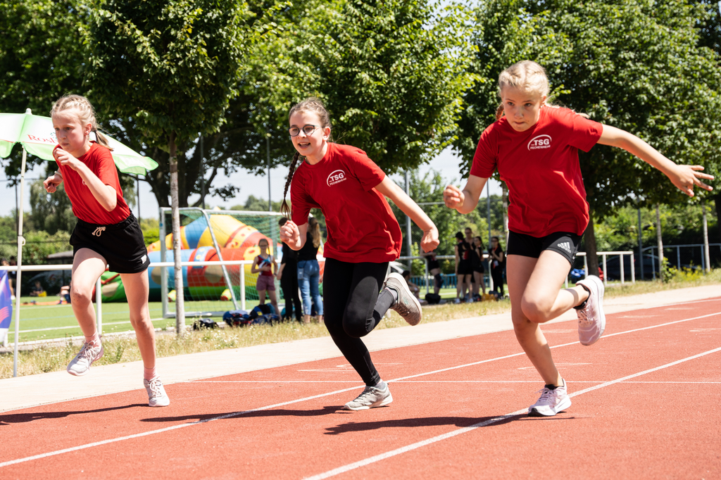 Drei Mädchen rennen bei einem Staffellauf um die Wette.