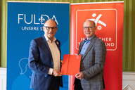 Bürgermeister und Präsident halten den Vertrag in den Händen. 