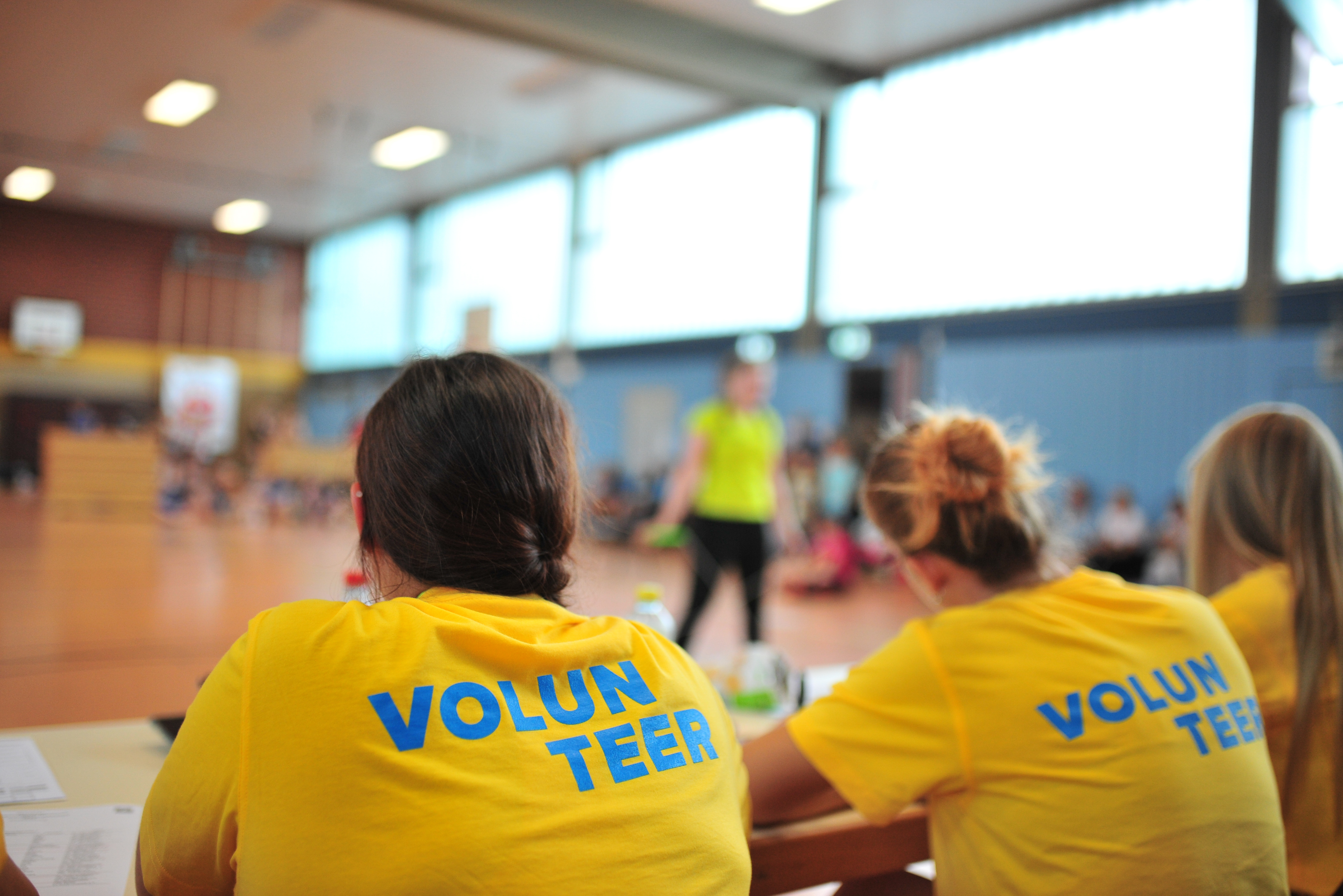 Mehrere Personen sitzen in einem gelben Volunteer-Shirt an einem Tisch.