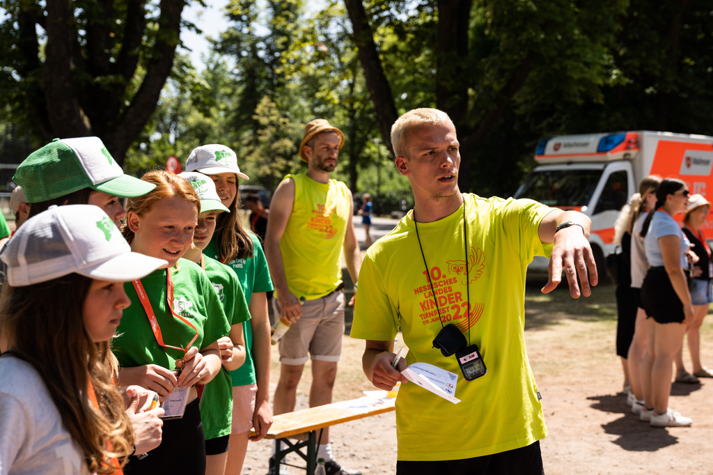 Ein Helfer zeigt Teilnehmenden den Weg.