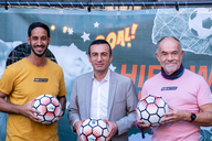 Drei Männer posieren mit einem Ball in der Hand für die Kamera.