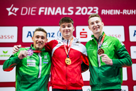 Drei Männer mit Medaillen bei einer Siegerehrung