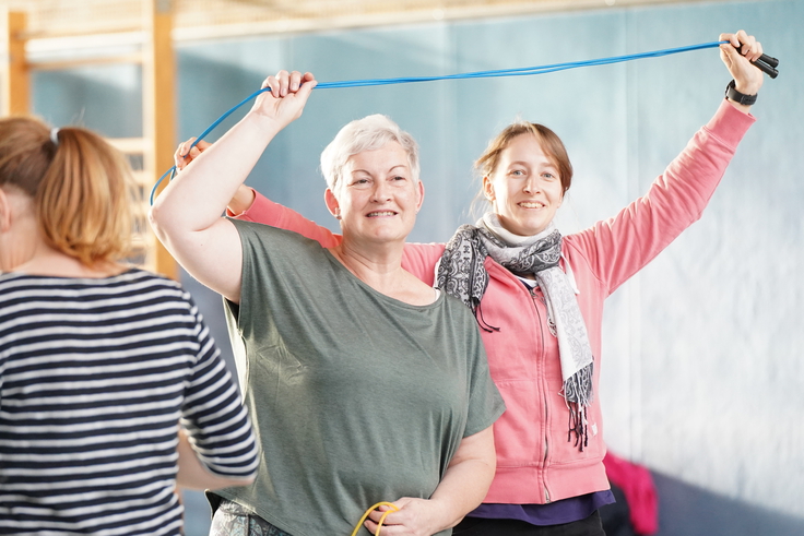 Zwei Frauen machen gemeinsam eine Übung mit einem Seil.