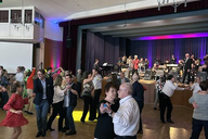 Eine Gruppe an Menschen tanzt in einem großen Saal.