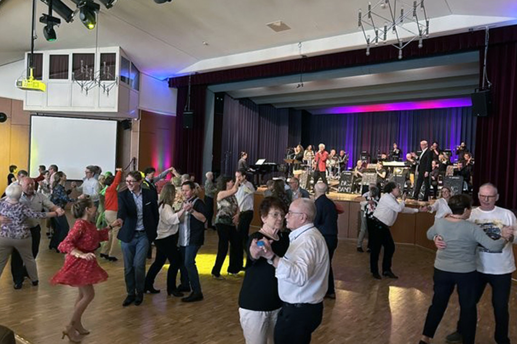Eine Gruppe an Menschen tanzt in einem großen Saal.