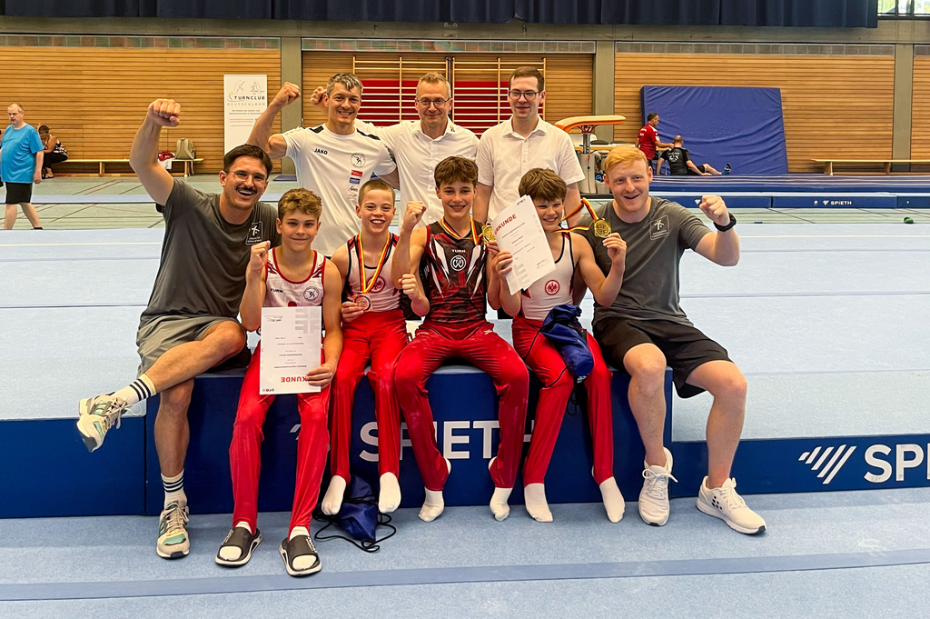 Teamfoto mit 4 Turnern und den jubelnden Trainern
