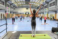 Gruppe von Frauen macht zusammen Sport in einer großen Sporthalle.