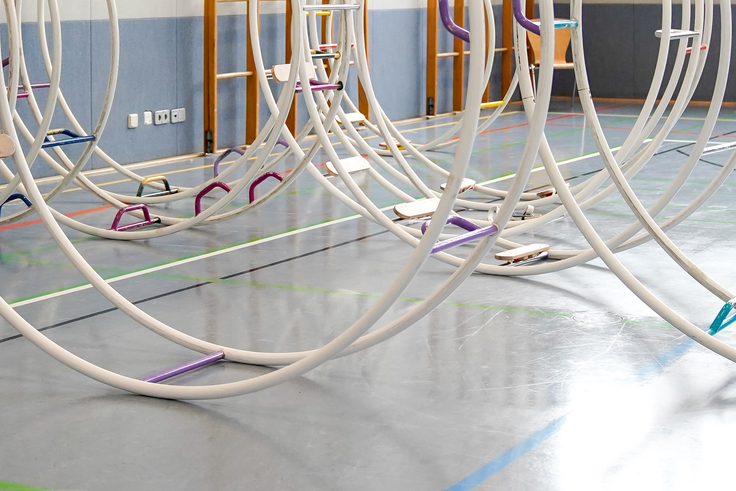 Mehrere Rhönräder stehen in einer Turnhalle nebeneinander.