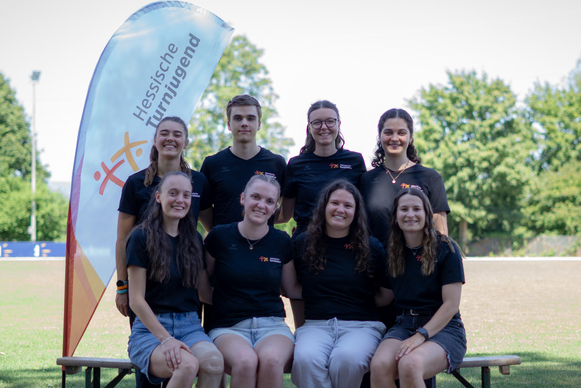Acht Personen posieren für ein Gruppenfoto. 