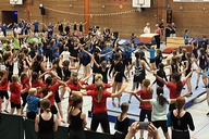 Viele Kinder stehen in einer Turnhalle und tanzen gemeinsam.