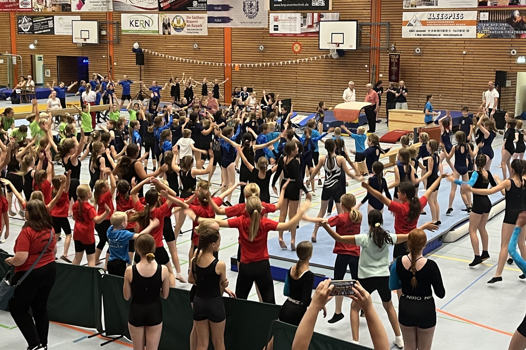 Viele Kinder stehen in einer Turnhalle und tanzen gemeinsam.