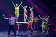 Showgruppe steht auf der Bühne und streckt die Arme in die Luft. 