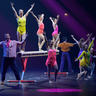 Showgruppe steht auf der Bühne und streckt die Arme in die Luft. 