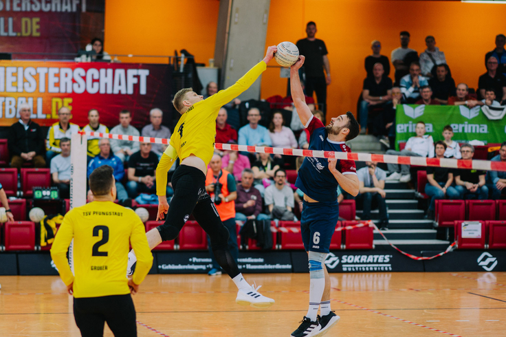 Zwei gegnerische Spieler treffen beide über dem Band den Ball