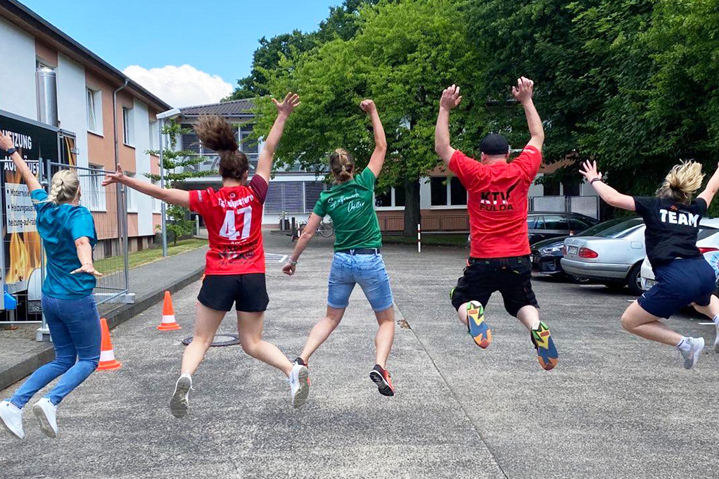 Personen sind in einer Reihe und springen hoch. Sie sind von hinten zu sehen.