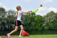 Mädchen spielt draußen mit einem Köcher und Ball.