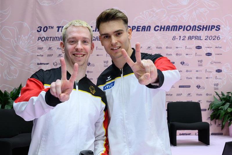 Zwei Männer posieren miteinander und zeigen das Victory-Zeichen