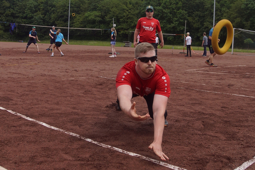 Ein Mann wirft sich auf einem Spielfeld nach einem Tennisring.
