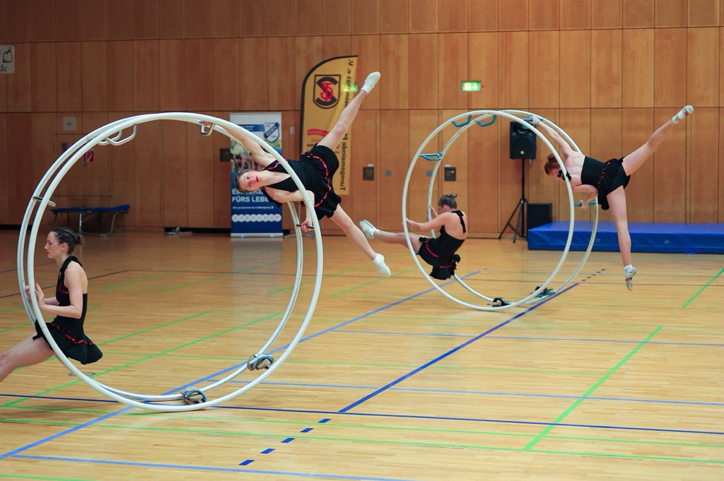 Vier Sportlerinnen zeigen ihre gemeinsame Übung in zwei Rhönrädern