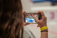 Ein Mädchen filmt eine Szene mit dem Smartphone in der Turnhalle.