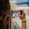 Ein Mädchen filmt eine Szene mit dem Smartphone in der Turnhalle.
