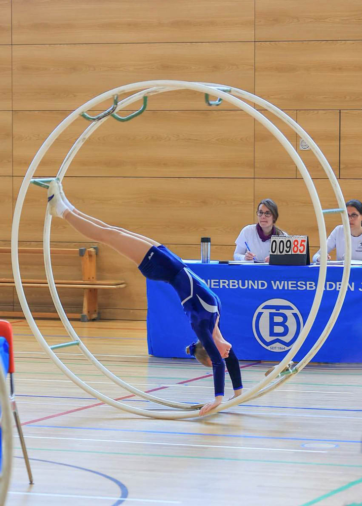 Turnerin steht kopfüber im Rhönrad