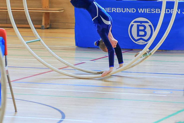 Turnerin steht kopfüber im Rhönrad