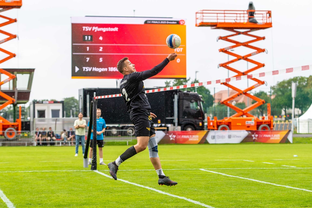 Faustballspieler beim Schlag, im Hintergrund große Leinwand