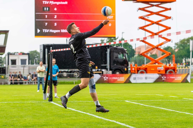 Faustballspieler beim Schlag, im Hintergrund große Leinwand