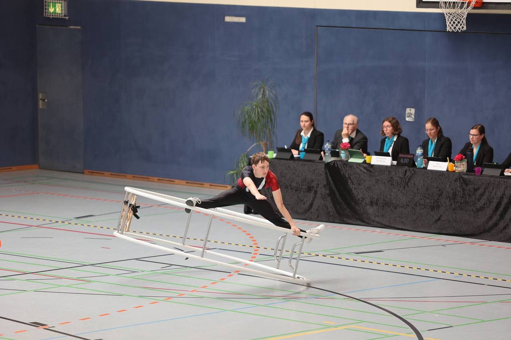Ein Turner bei der Übung im Rhönrad, welches seitlich liegt