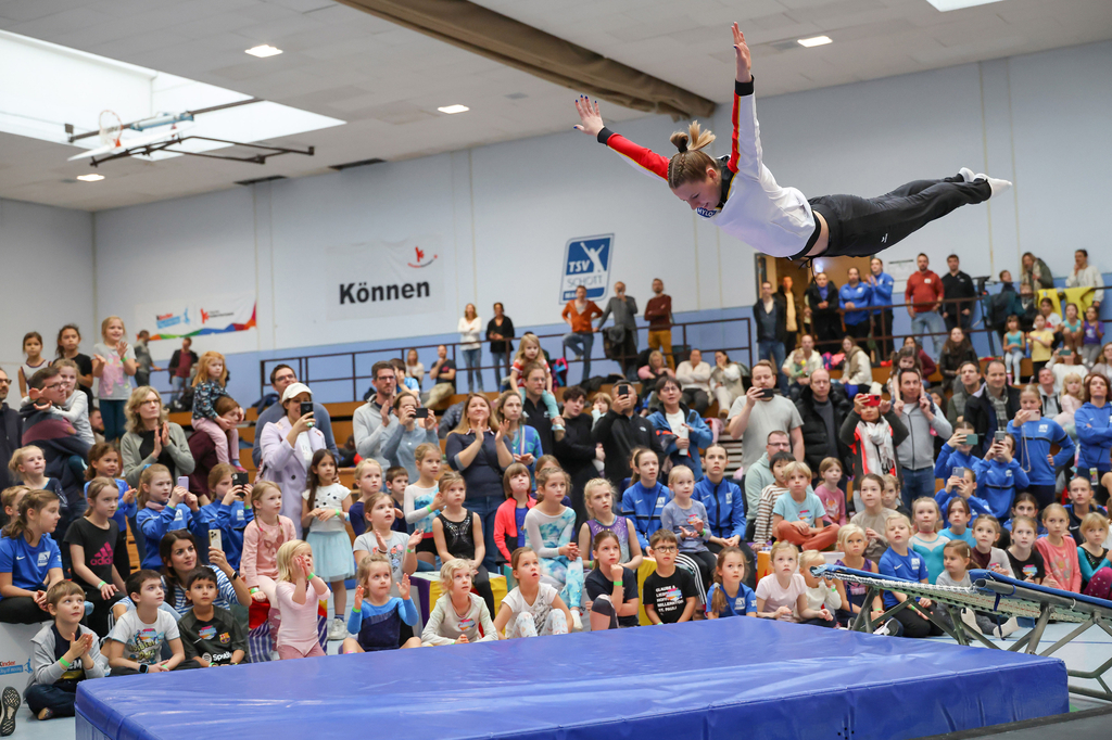 Die Turnerin Maya Möller zeigt Kindern Turnelemente auf dem Mini-Trampolin.
