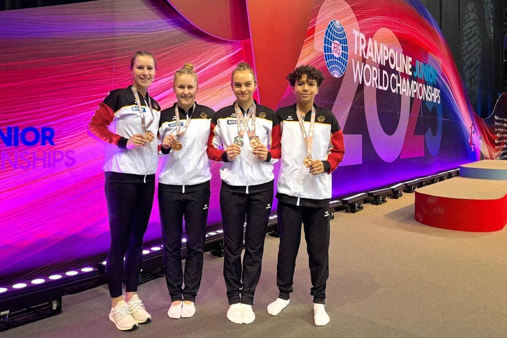 Vier jugendliche stehen neben einander mit ihren Medaillen in der Hand vor der LED-Wand "Trampoline World Championships"
