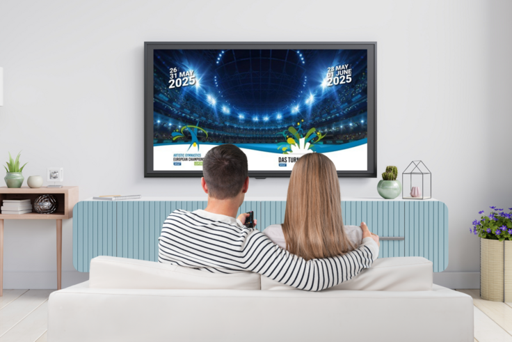 Ein Pärchen sitzt auf einem Sofa vor dem Fernsehen. 