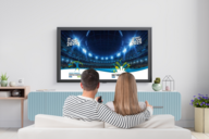 Ein Pärchen sitzt auf einem Sofa vor dem Fernsehen. 