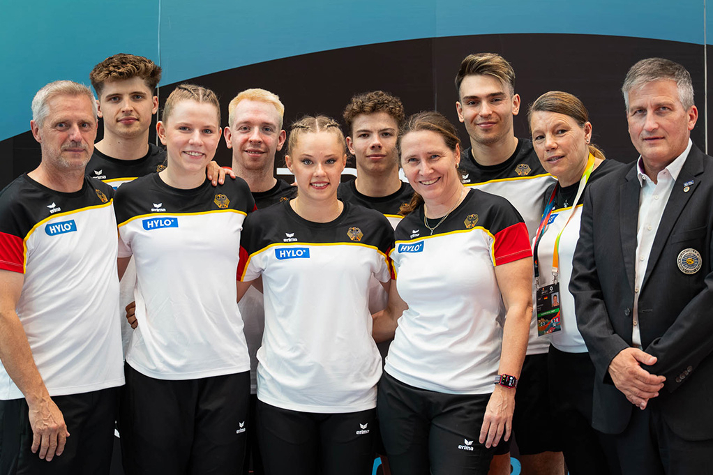 Die Trampolinturner*innen posieren für ein Foto mit ihren Trainer*innen.