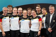 Die Trampolinturner*innen posieren für ein Foto mit ihren Trainer*innen. 