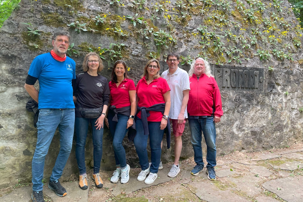 Sechs Personen stehen nebeneinander vor dem Denkmal