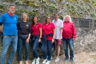 Sechs Personen stehen nebeneinander vor dem Denkmal