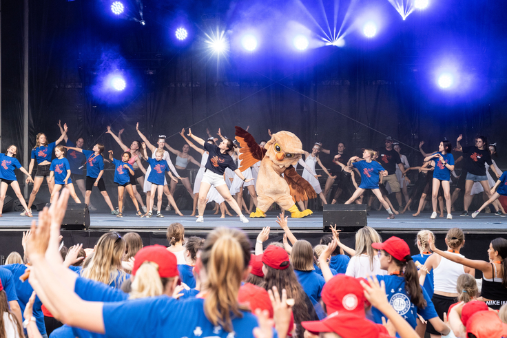 Eine Bühne im Freien, vor der viele Menschen stehen und tanzen.