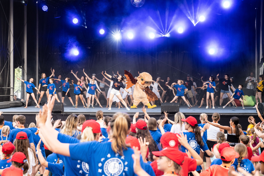 Eine Bühne im Freien, vor der viele Menschen stehen und tanzen.