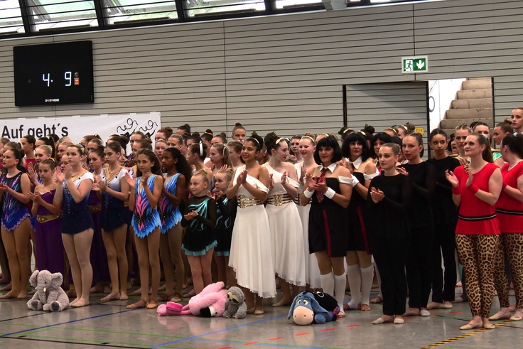Mehrere Tanzgruppen stehen aufgereiht nebeneinander.