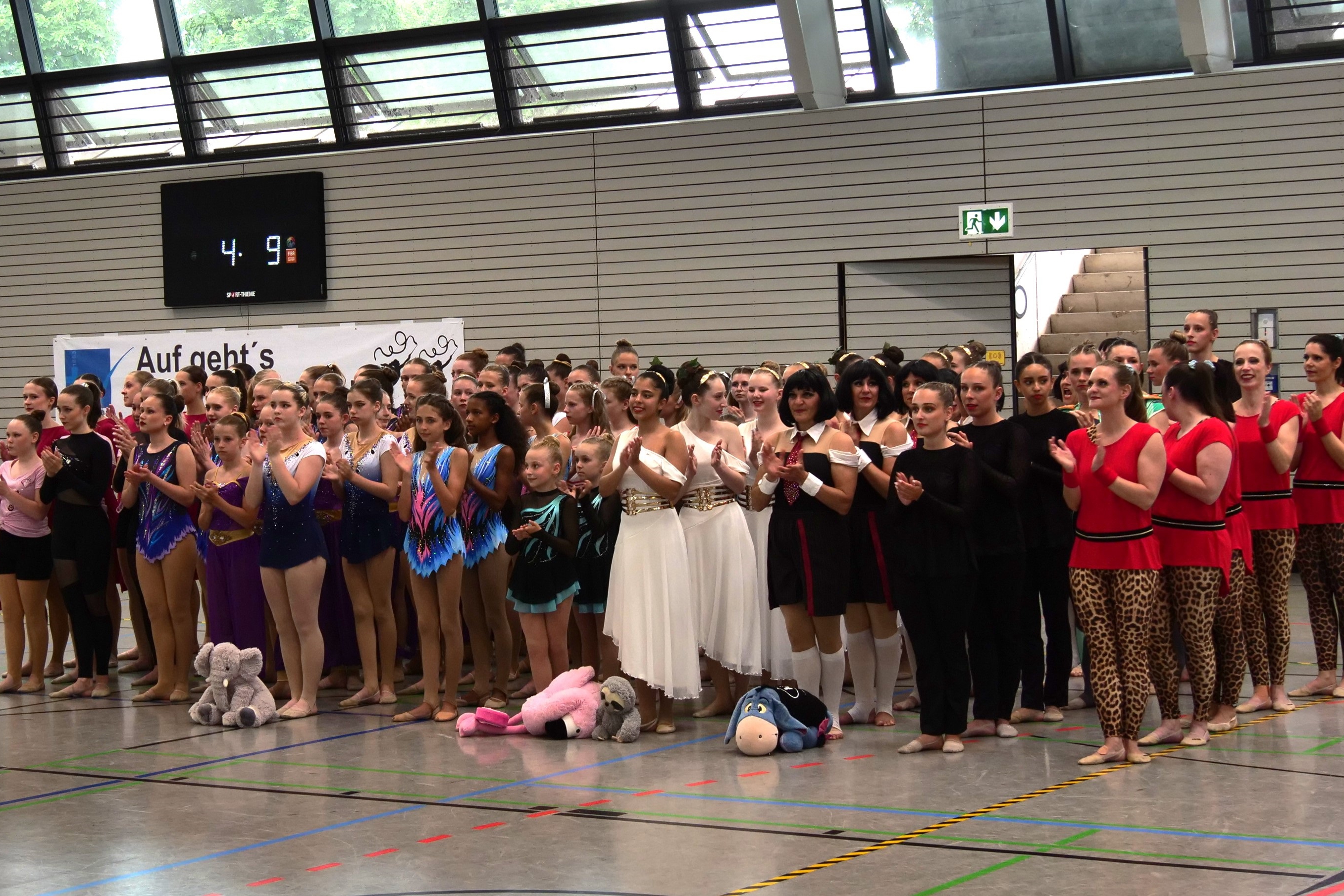 Mehrere Tanzgruppen stehen aufgereiht nebeneinander.
