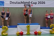 Sechs Gymnastinnen stehen auf einem Podest bei der Siegerehrung.