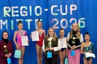 Gymnastinnen posieren auf einem Podest.