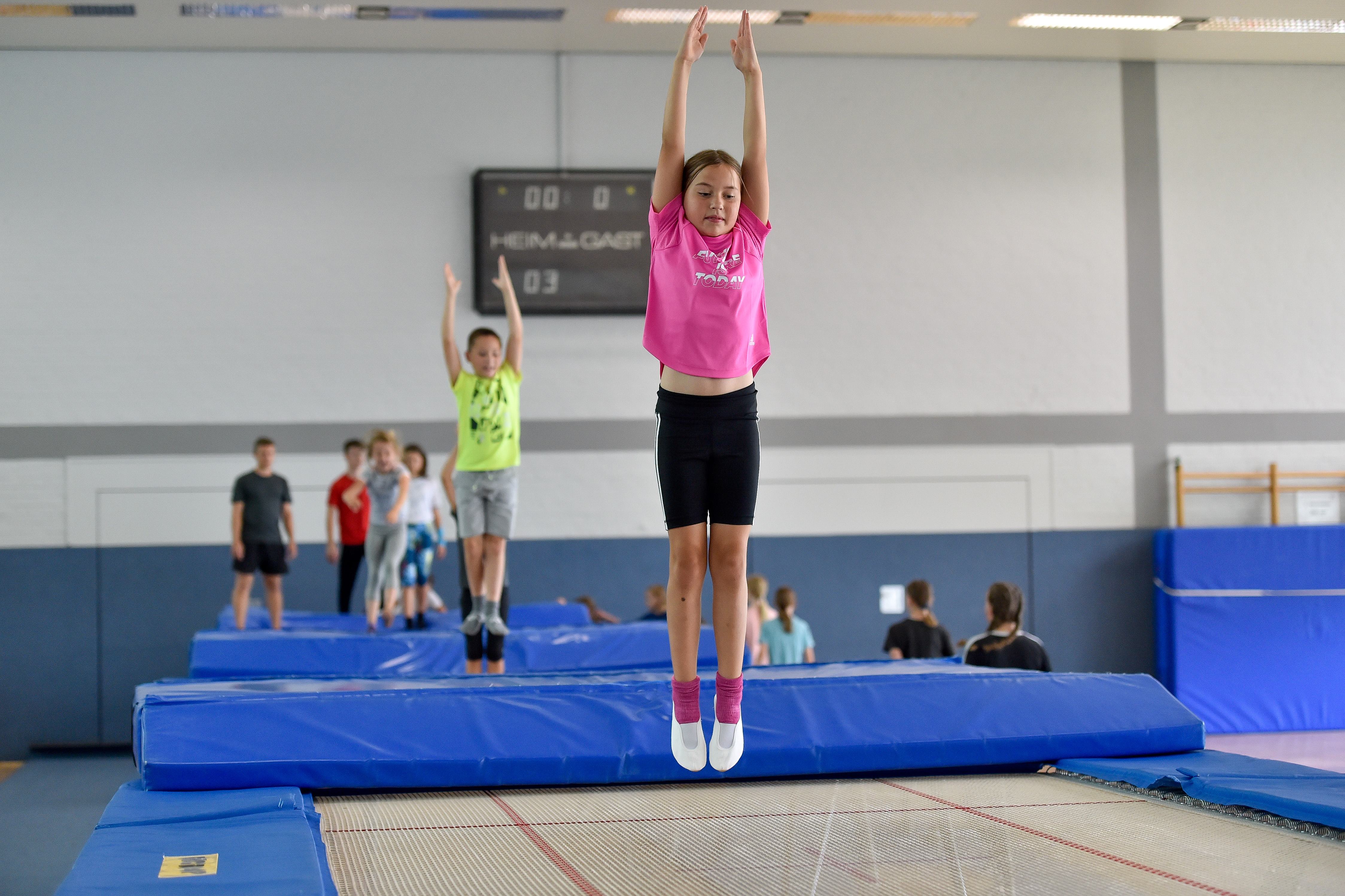 Mehrere Kinder springen nacheinander auf einer Trampolinbahn.