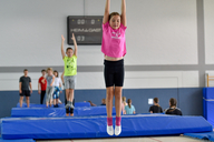 Mehrere Kinder springen nacheinander auf einer Trampolinbahn.