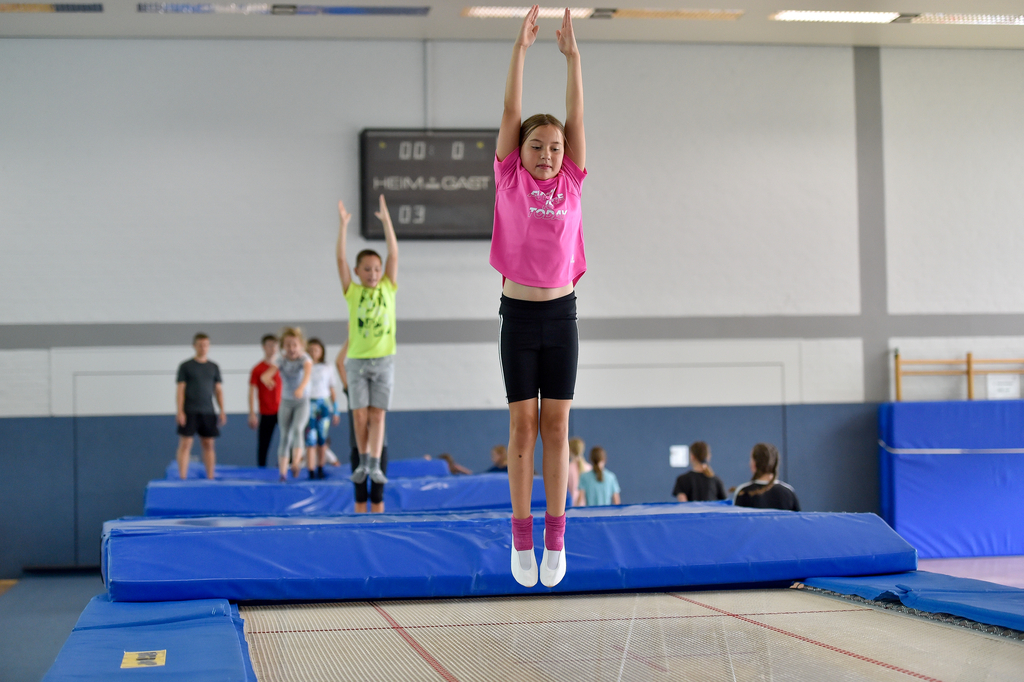 Mehrere Kinder springen nacheinander auf einer Trampolinbahn.