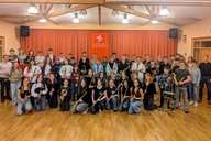 Eine Gruppe an Menschen posiert mit ihren Instrumenten für ein Foto.